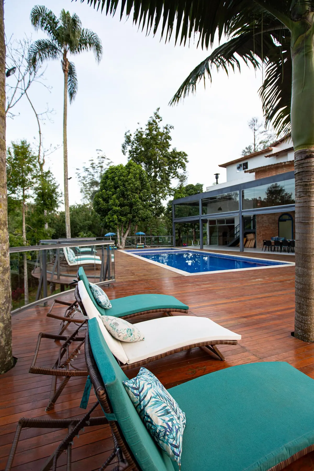 Deck de madeira das piscinas, com espreguiçadeiras e a mata ao fundo